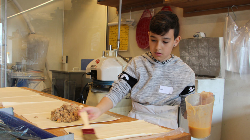 Junge bepinselt Teig von Apfelstrudel