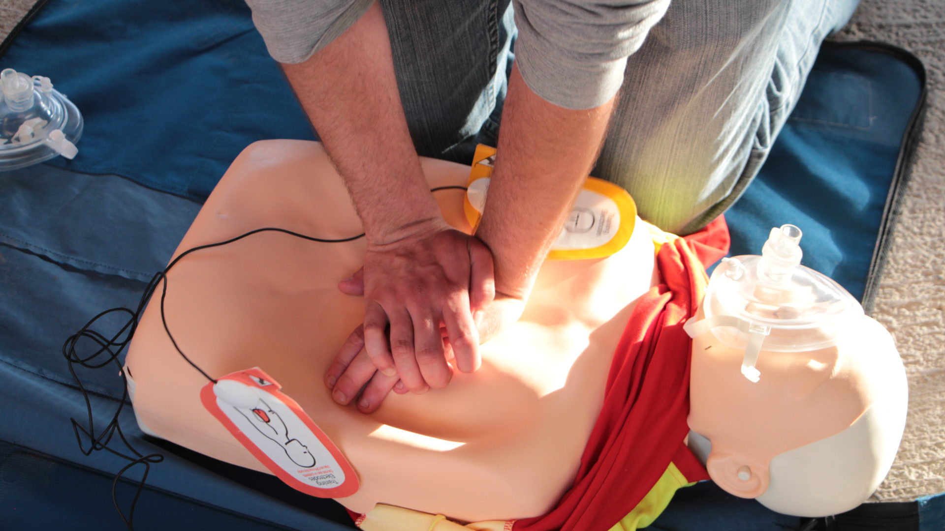 Person übt Herzmassage an Dummy aus